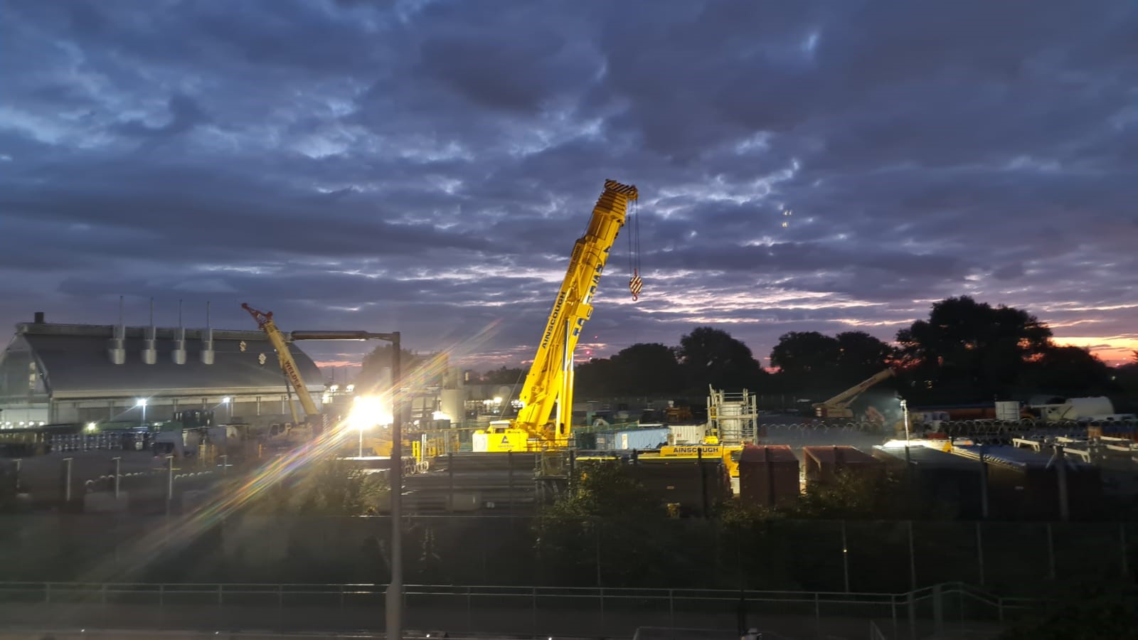 Ainscough mobile crane illuminated at a construction site at dusk